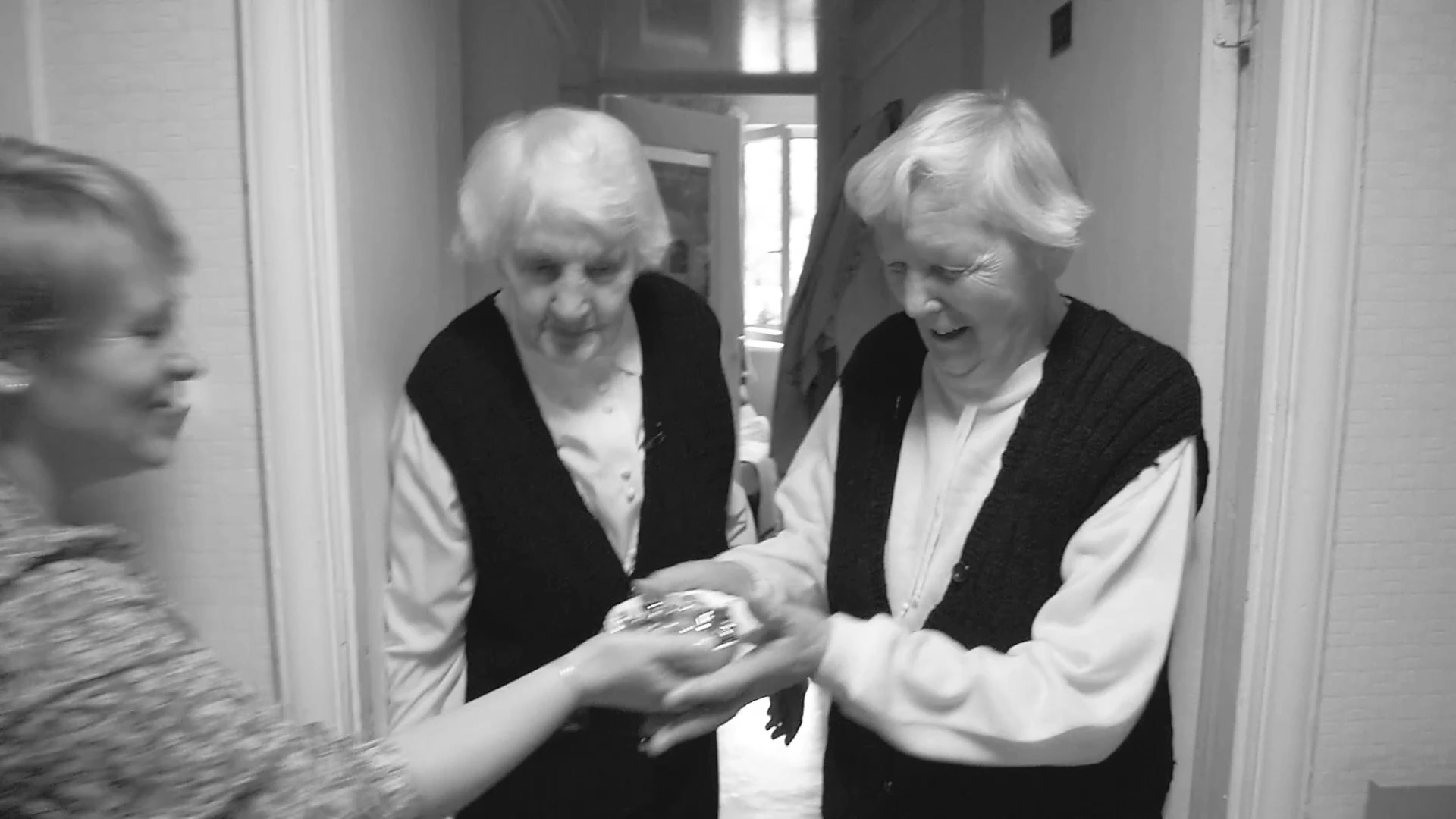 Two women sharing a plate with a visitor in MONUMENT.